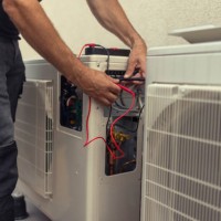 an unrecognizable electrician installs a heat pump in the courtyard of a residential building - home decoration stock pictures, royalty-free photos & images