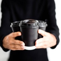 an unrecognizable man holding three disposable and black paper coffee cups with lids on - junk food stock pictures, royalty-free photos & images