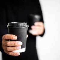 an unrecognizable man holding two disposable and black paper coffee cups - junk food stock pictures, royalty-free photos & images
