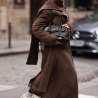 Anna Wein is seen wearing rimless oversized sunglasses with brown lenses, slim gold metal temples, and a gold metal nose bridge from Miu Miu; chunky...