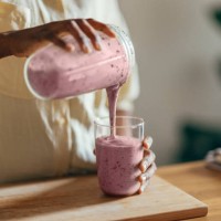 anonymous afro-american woman pouring a smoothie into a glass - food stock pictures, royalty-free photos & images