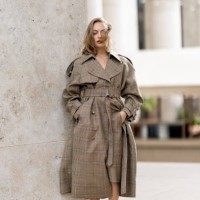 Anouchka Gauthier wears a beige checked coat and white heeled sandals outside Zimmermann show during Womenswear Spring/Summer 2025 as part of Paris...