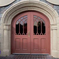arched entrance door with windows and rustic stone walls, with street lamps and green bushes. - garden decoration stockfoto's en -beelden