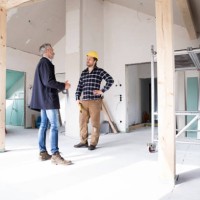 architect and construction worker discussing while standing in renovating house - home decoration stockfoto's en -beelden