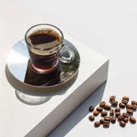 aromatic morning coffee in glass cup and a long shadow from the cup on beige color background. - coffee stock pictures, royalty-free photos & images
