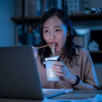 asia freelance smart business women eating instant noodles while working on laptop in living room at home at night - junk food stock pictures, royalty-free photos & images