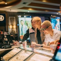 asian bartender serving a gay couple in front bar counter for popcorn before movie show time at movie theater cinema. - junk food stock pictures, royalty-free photos & images