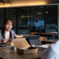 asian business woman having take away food with colleague at office lounge during lunch break - junk food stock pictures, royalty-free photos & images