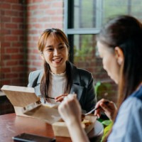 asian businesswoman eating take away lunch with her colleague - junk food stock pictures, royalty-free photos & images