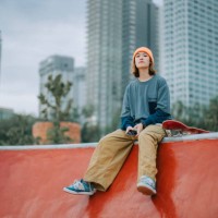 asian chinese female skateboarder sitting at skateboard park looking away - fashion stock pictures, royalty-free photos & images