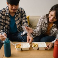 asian couple having lunch at home during quarantine. - junk food stock pictures, royalty-free photos & images