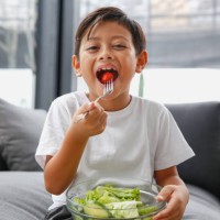 asian little boy eating healthy green salad - food stock pictures, royalty-free photos & images