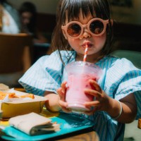 asian little girl in sunglasses drinking smoothie in restaurant - junk food stock pictures, royalty-free photos & images