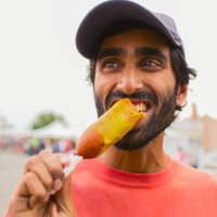 asian man eating corn dog outdoors - food stock pictures, royalty-free photos & images