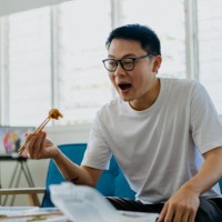 asian man eating home delivery meal in living room - junk food stock pictures, royalty-free photos & images