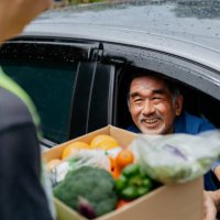 asian senior man receiving donated groceries from volunteer at drive through food bank - food stock pictures, royalty-free photos & images