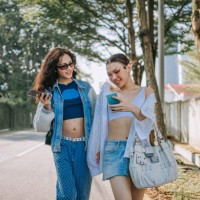 asian transgender female friends holding smart phone walking on the street in the morning - fashion stock pictures, royalty-free photos & images