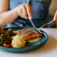 asian woman eating pan fried salmon in cafe - food stock pictures, royalty-free photos & images