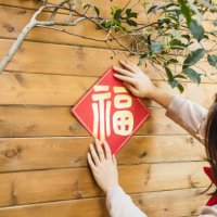 asian woman hanging chinese new year decoration (“福”) on the wall of the front/back yard - garden decoration stock pictures, royalty-free photos & images