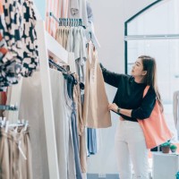 asian woman trying clothes for decision. woman looking at casual clothing while shopping in clothing store. - fashion stock pictures, royalty-free photos & images