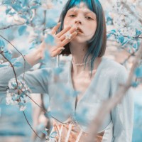 asian woman with blue hair on the background of a flowering tree. bang hairstyle. spring garden. white flowers - fashion stock pictures, royalty-free photos & images