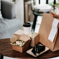 assorted fresh and healthy takeaway meals delivered at home, with healthy grilled chicken vegetable salad, japanese style rice ball / onigiri and a cup of coffee freshly served on the coffee table - junk food stock pictures, 