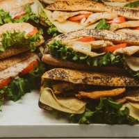assortment of chicken sandwiches with cheese, tomatoes, and lettuce on display - junk food stock pictures, royalty-free photos & images
