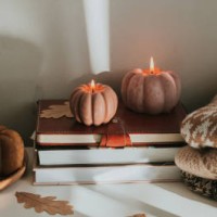 atmospheric candles shape of pumpkin, stack warm sweaters, autumn decor on table. cozy autumn lifestyle, hygge concept. still life. - home decoration stock-fotos und bilder