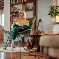 attractive young adult woman reading book in living room. - home decoration stock pictures, royalty-free photos & images