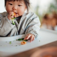 baby girl learning to feed herself with finger foods - food stock pictures, royalty-free photos & images