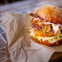 bacon cheeseburger with salad in bun, served on wooden board - junk food stock pictures, royalty-free photos & images