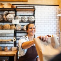 bakery owner giving food package to customer - junk food stock pictures, royalty-free photos & images