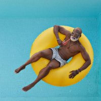 bald man relaxing in yellow inflatable ring - travel stock-fotos und bilder