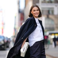 Bambi Northwood Blyth wears white oversized Calvin Klein jean print shirt, black oversized coat, shiny black leather belt, black high waisted relaxed...
