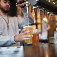 Bartender pours pints for takeaway customers at The Ten Bells pub in east London on June 27, 2020. - The pub serves drinks for takeaway to maintain...