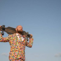 bearded man with longboard on his shoulders wearing suit with colourful polka-dots - fashion stock pictures, royalty-free photos & images