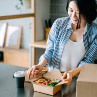 beautiful and joyful young asian woman opening the takeaway lunch box of fresh healthy salad, eating at home with food delivery services. eating at home concept - junk food stock pictures, royalty-free photos & images
