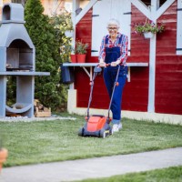 beautiful mature women using a lawn mower in her backyard cutting the grass - garden decoration stock pictures, royalty-free photos & images