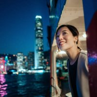 beautiful smiling young asian woman looking out through the window, enjoying spectacular illuminated night view of the city while travelling by ferry - travel stock-fotos und bilder
