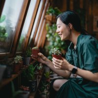 beautiful smiling young asian woman taking care of her houseplants in the balcony. enjoying her time at home. going green lifestyle - home decoration stock pictures, royalty-free photos & images