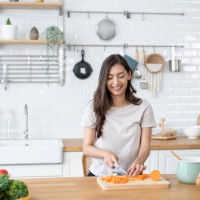 beautiful woman cutting ingredients for a meal in the kitchen - food stock pictures, royalty-free photos & images