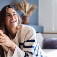 beautiful woman is enjoying a relaxing day at home, smiling brightly while lounging on her comfortable sofa - home decoration stock pictures, royalty-free photos & images