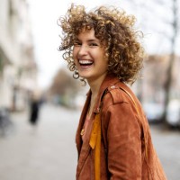 beautiful woman walking outdoors looking behind and laughing - fashion stock pictures, royalty-free photos & images