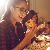 beautiful young woman enjoying her burger - junk food stock pictures, royalty-free photos & images