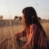 beautiful young woman enjoying the sunlight while sitting in high grass - fashion stock pictures, royalty-free photos & images