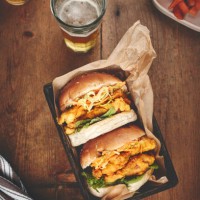 beer, burger and takeaway on a wooden table and fast food with chicken and diner meal. glass, alcohol and dinner with a basket or grill with luxury or eating with restaurant and delicious with supper - junk food stock picture