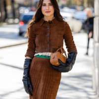 Belen Hostalet wears brown suede skirt, jacket, black gloves, bag, green knitted socks outside Miu Miu during Womenswear Spring/Summer 2025 as part...