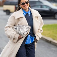 Benthe Liem wears beige coat, dark denim jeans, denim shirt, bag with dots print outside Marimekko during the Copenhagen Fashion Week Autumn/Winter...