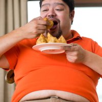 übergewichtiger mann isst samosa - junk food stock-fotos und bilder