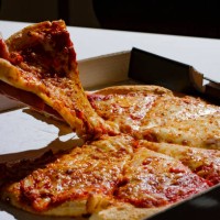 Berlin, Germany Symbolic photo on the subject of unhealthy food. A piece of pizza with a lot of cheese is taken out of a pizza box on February 13,...